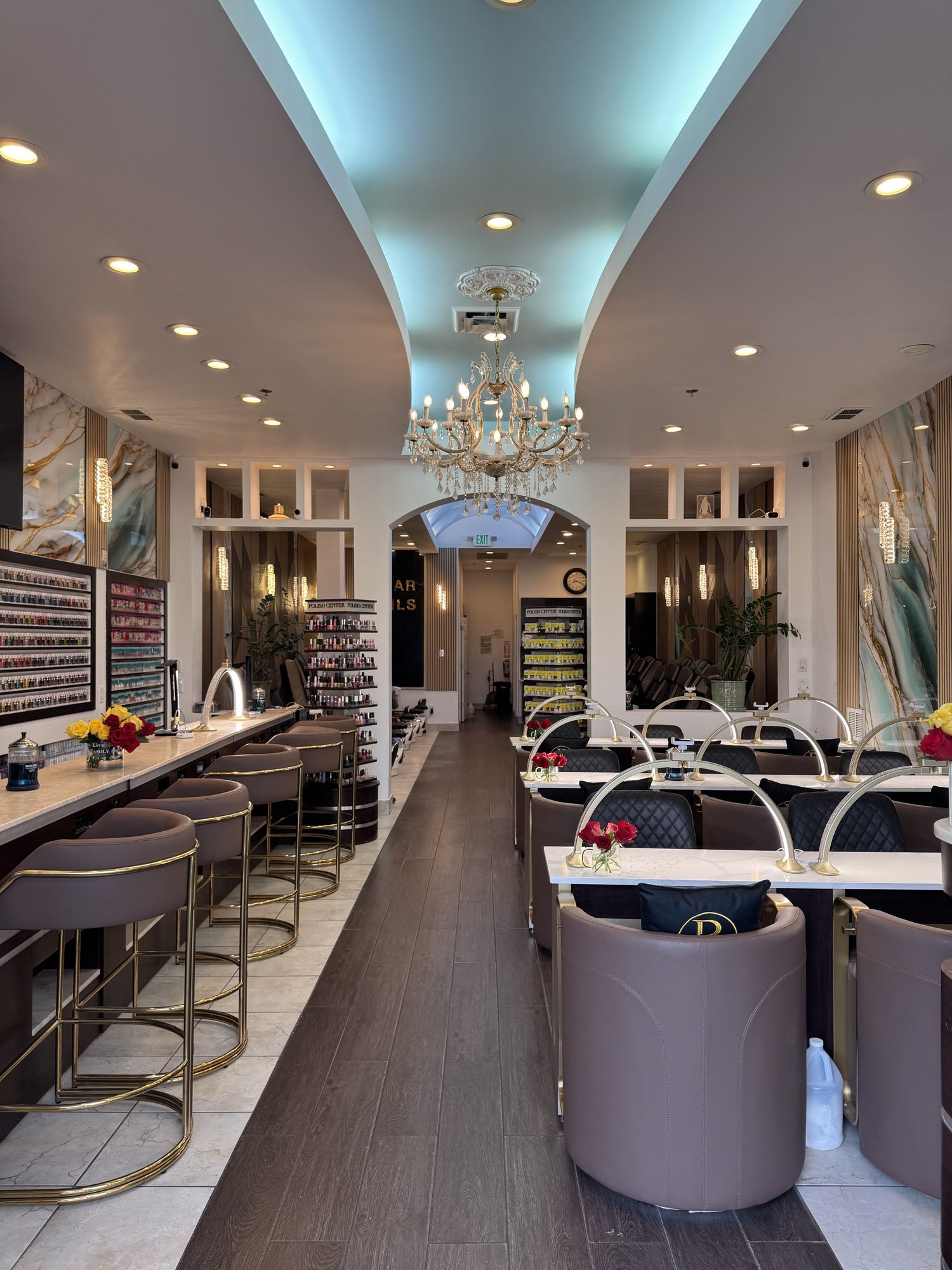 The renovated interior of Bar Nails & Spa with marble walls and a crystal chandelier down the center aisle